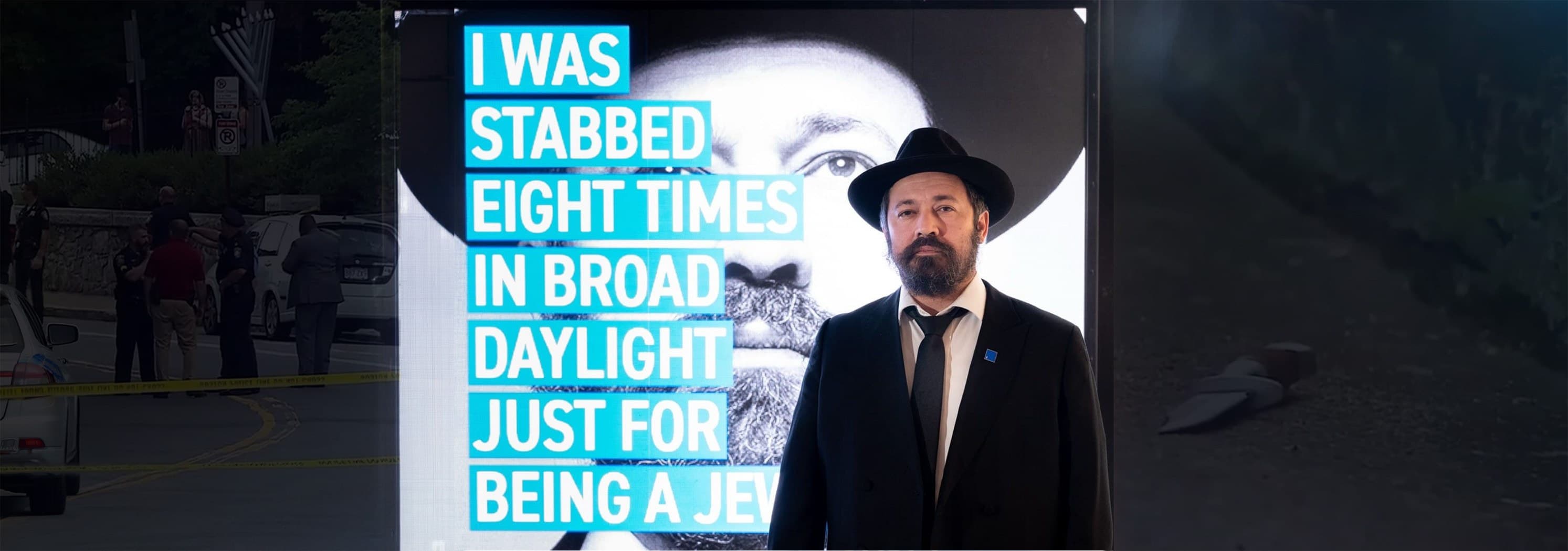 Rabbi Shlomo Noginski beside a display featuring his own quote about the attack he survived