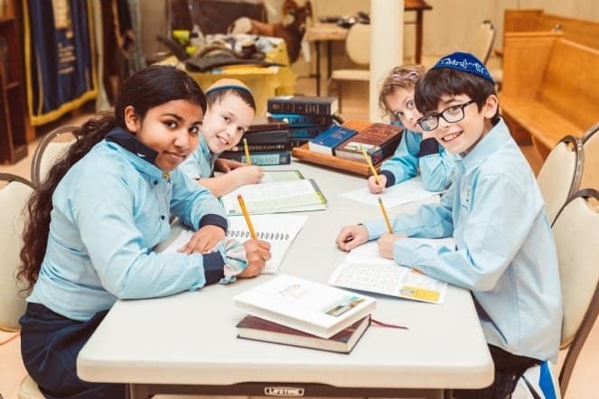 Children studying together at a classroom table at Shaloh House
